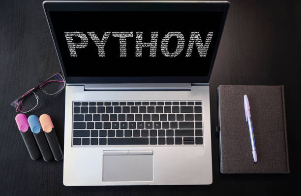 Laptop with python lettering on table with notepad and markers